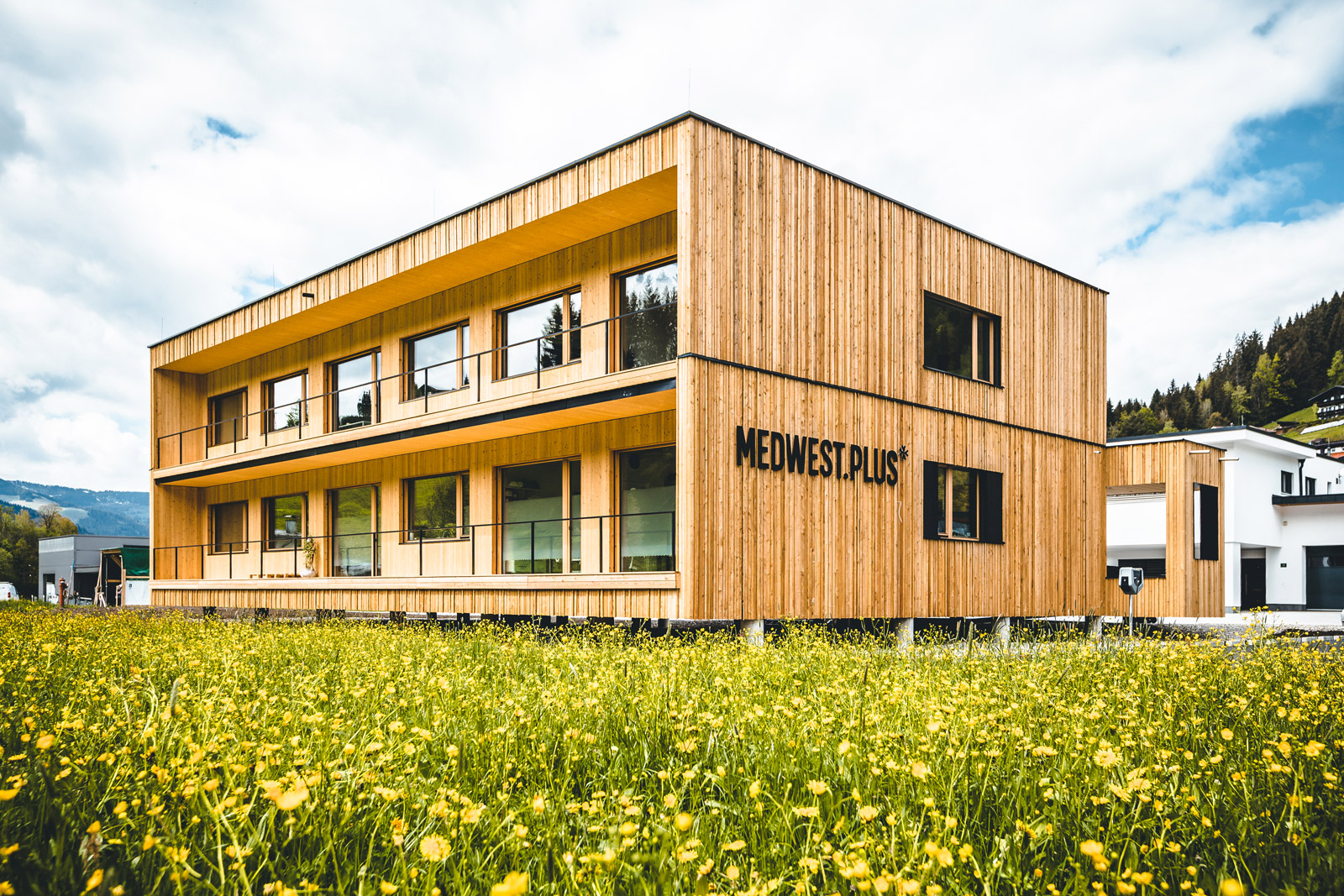 Außenansicht des Holzgebäudes mit Balkonen und Parkbereich