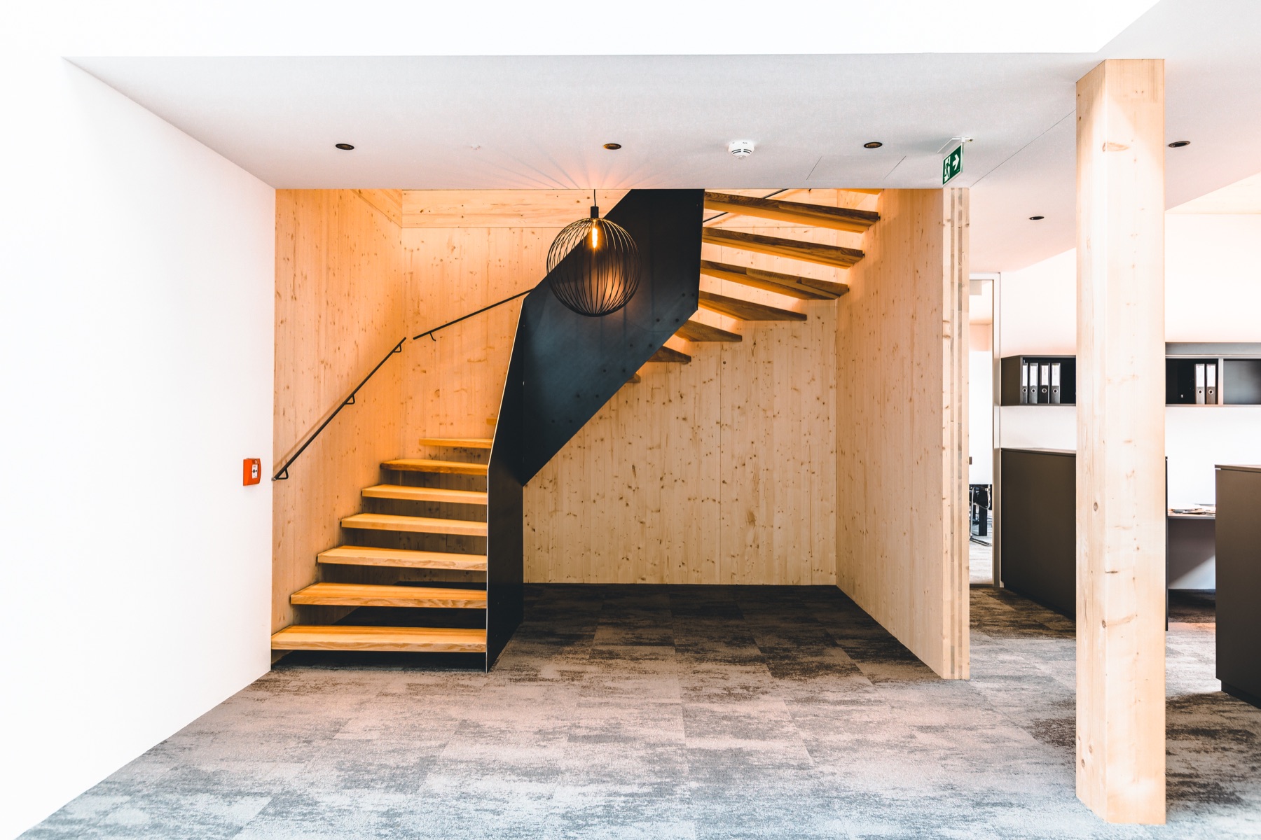 Moderner Eingangsbereich mit Holztreppe und schwarzer Stahlwange