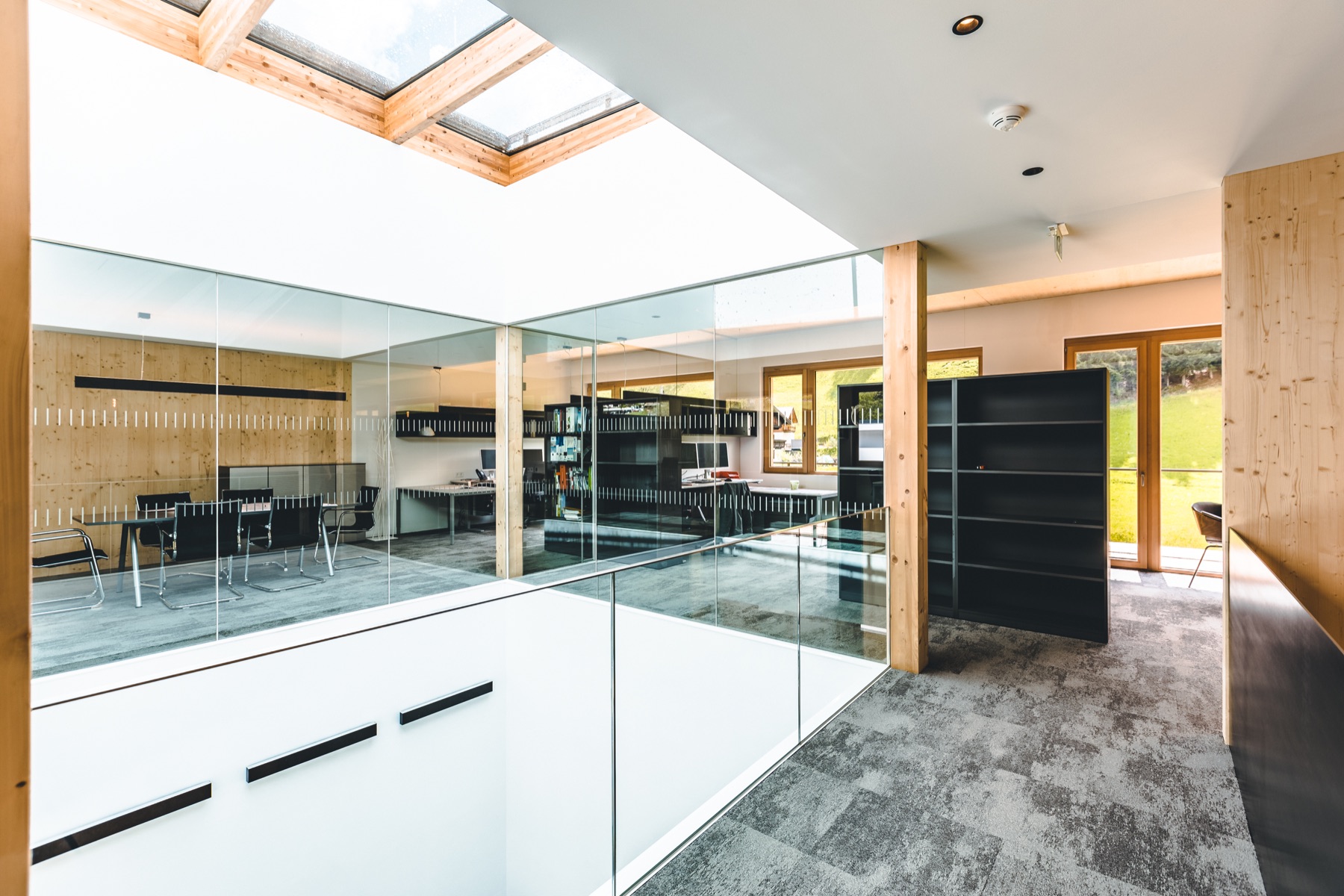 Helle Bürozone mit Glaswand, Holzdecken und Arbeitsplätzen