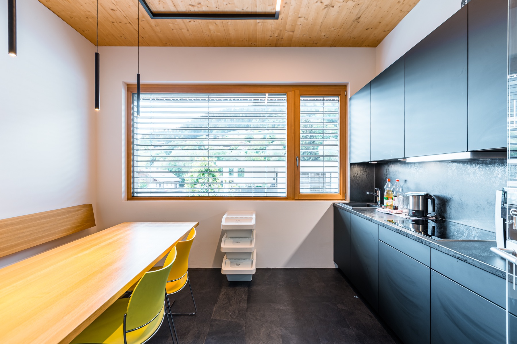 Gemeinschaftsküche mit Holzdecke, Fenster und dunkler Küchenzeile