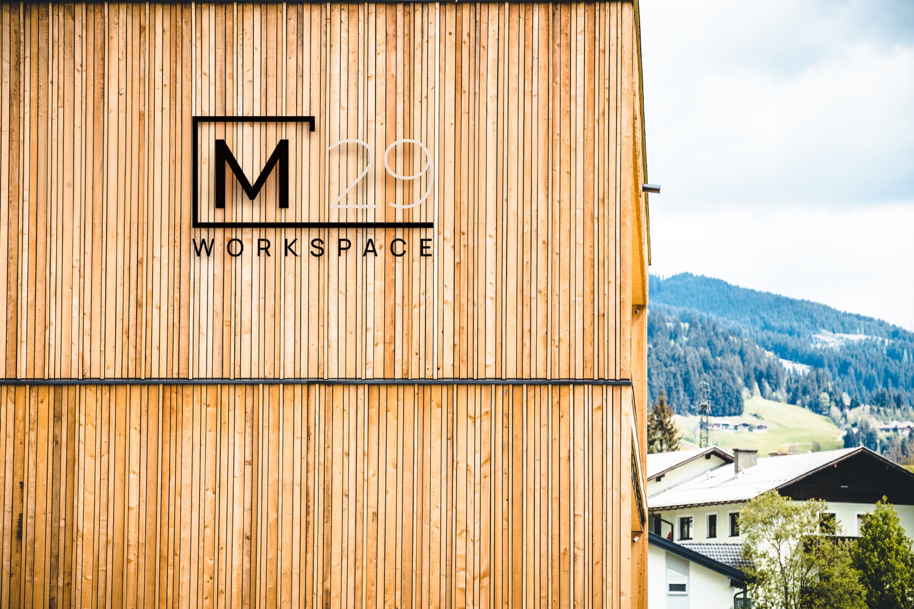 M29 Workspace Logo an der Holzfassade mit Blick auf die Umgebung