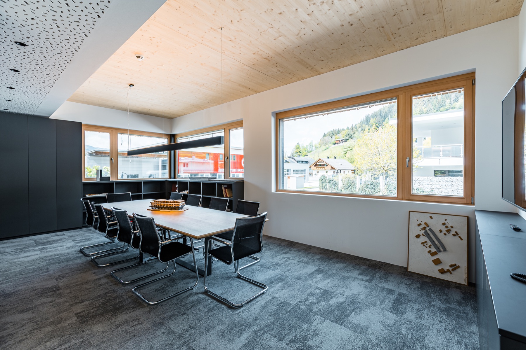 Besprechungsraum mit großem Tisch, Holzdecke und Fensterfront